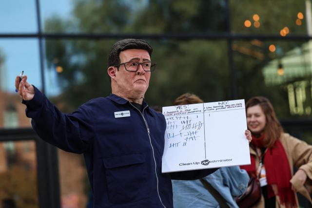A man wearing a mask of Britain's Prime Minister Andy Burnham protests about private donations, on the sidelines of the second day of the annual Labour Party conference in Liverpool, north-west England, on September 28, 2026. (Photo by Darren Staples / AFP)