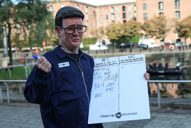 A man wearing a mask of Britain's Prime Minister Andy Burnham protests about private donations, on the sidelines of the second day of the annual Labour Party conference in Liverpool, north-west England, on September 28, 2026. (Photo by Darren Staples / AFP)
