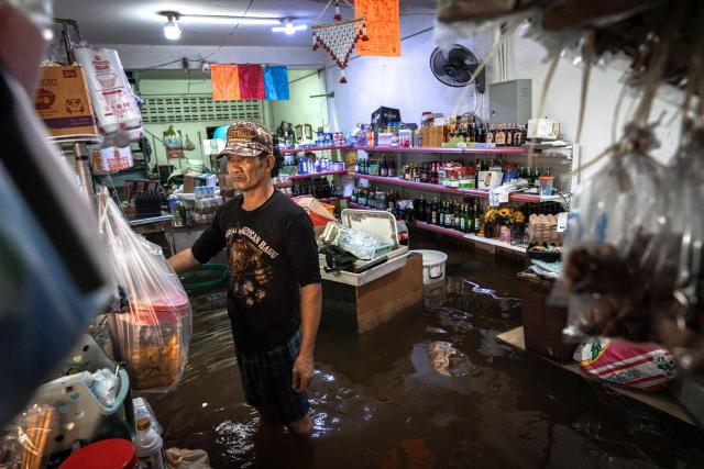 A grocery store owner stands inside his flooded shop in the Bang Kapi district of Bangkok on September 28, 2026. More than 500,000 households and 1.7 million people across 27 provinces are currently affected by floods in Thailand after an intense weather system hit the region, the government said. (Photo by Chanakarn LAOSARAKHAM / AFP)