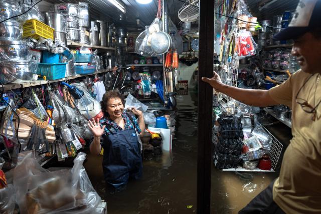 A store owner speaks to a man inside her flooded shop in the Bang Kapi district of Bangkok on September 28, 2026. More than 500,000 households and 1.7 million people across 27 provinces are currently affected by floods in Thailand after an intense weather system hit the region, the government said. (Photo by Chanakarn LAOSARAKHAM / AFP)