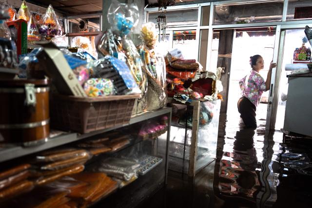 A Buddhist supplies store owner stands inside her flooded shop in the Bang Kapi district of Bangkok on September 28, 2026. More than 500,000 households and 1.7 million people across 27 provinces are currently affected by floods in Thailand after an intense weather system hit the region, the government said. (Photo by Chanakarn LAOSARAKHAM / AFP)