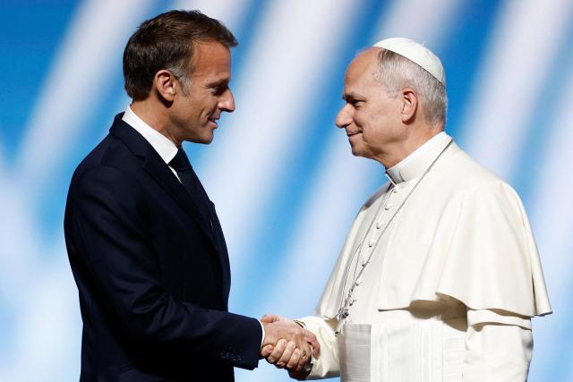 Pope Leo XIV (R) is welcomed by France's President Emmanuel Macron as he arrives on stage at the opening of a meeting called "At the Roots of Europe: For Peace and Unity" at the Robert Schuman Conference Centre in Metz, northeastern France, on September 28, 2026 on the last day of his visit to France. (Photo by Benoit Tessier / POOL / AFP)