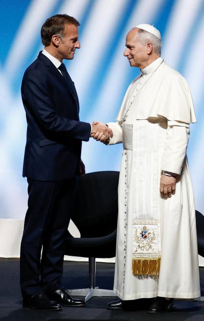 Pope Leo XIV (R) is welcomed by France's President Emmanuel Macron as he arrives on stage at the opening of a meeting called "At the Roots of Europe: For Peace and Unity" at the Robert Schuman Conference Centre in Metz, northeastern France, on September 28, 2026 on the last day of his visit to France. (Photo by Benoit Tessier / POOL / AFP)