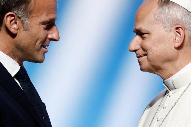 Pope Leo XIV (R) is welcomed by France's President Emmanuel Macron as he arrives on stage at the opening of a meeting called "At the Roots of Europe: For Peace and Unity" at the Robert Schuman Conference Centre in Metz, northeastern France, on September 28, 2026 on the last day of his visit to France. (Photo by Benoit Tessier / POOL / AFP)