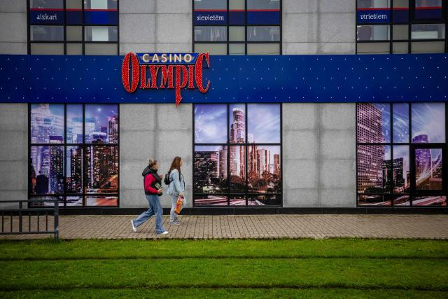 A couple walk past the Olympic Casino in the centre of Daugavpils, Latvia, on September 26, 2026, ahead of the country's parliamentary elections on October 3. Latvia goes to the polls for parliamentary elections on October 3, 2026. (Photo by Wojtek RADWANSKI / AFP)