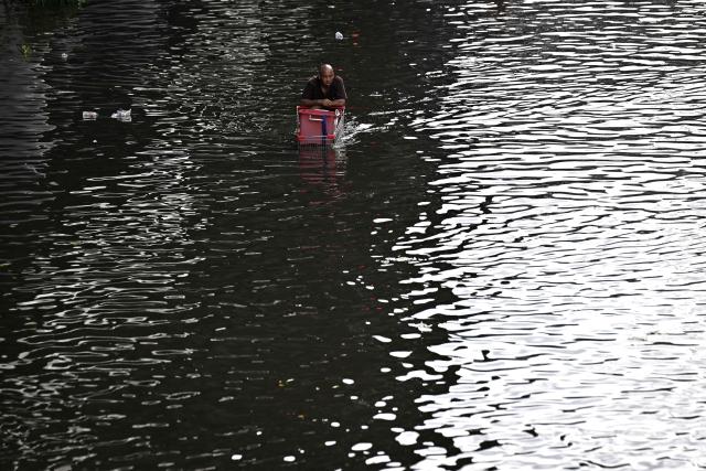 A resident pushes a trolley while navigating floodwaters in Bang Kapi district in Bangkok on September 28, 2026. More than 500,000 households and 1.7 million people across 27 provinces are currently affected by floods in Thailand after an intense weather system hit the region, the government said. (Photo by Lillian SUWANRUMPHA / AFP)