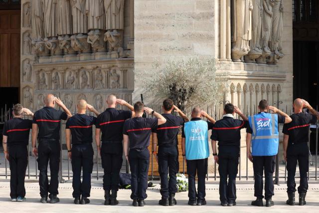 Firefighters observe a minute of silence after laying a wreath in memory of firefighters killed while battling wildfires in France, in front of Notre-Dame de Paris Cathedral during a protest called by a broad coalition of unions campaigning for higher pay and increased budgetary resources, in Paris, on September 28, 2026. Professional firefighters, who are local government employees, together with around 200,000 volunteer firefighters, are calling for increased recruitment, stronger health protections, and a clearer focus on their core duties. (Photo by Xavier GALIANA / AFP)