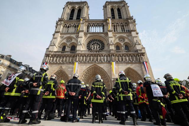 Firefighters observe a minute of silence in memory of their comrades killed while battling wildfires in France, in front of Notre-Dame de Paris Cathedral during a protest called by a broad coalition of unions campaigning for higher pay and increased budgetary resources, in Paris, on September 28, 2026. Professional firefighters, who are local government employees, together with around 200,000 volunteer firefighters, are calling for increased recruitment, stronger health protections, and a clearer focus on their core duties. (Photo by Xavier GALIANA / AFP)