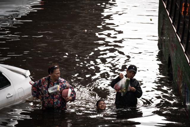 People walk through floodwaters in the Bang Kapi district of Bangkok on September 28, 2026. More than 500,000 households and 1.7 million people across 27 provinces are currently affected by floods in Thailand after an intense weather system hit the region, the government said. (Photo by Chanakarn LAOSARAKHAM / AFP)