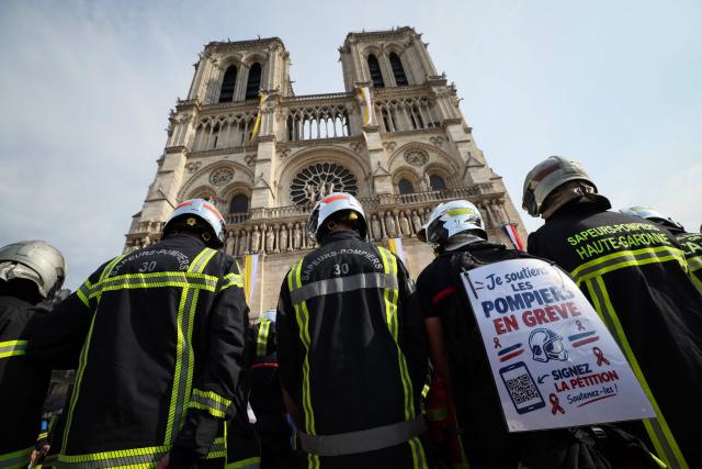 Firefighters observe a minute of silence in memory of their comrades killed while battling wildfires in France, in front of Notre-Dame de Paris Cathedral during a protest called by a broad coalition of unions campaigning for higher pay and increased budgetary resources, in Paris, on September 28, 2026. Professional firefighters, who are local government employees, together with around 200,000 volunteer firefighters, are calling for increased recruitment, stronger health protections, and a clearer focus on their core duties. (Photo by Xavier GALIANA / AFP)