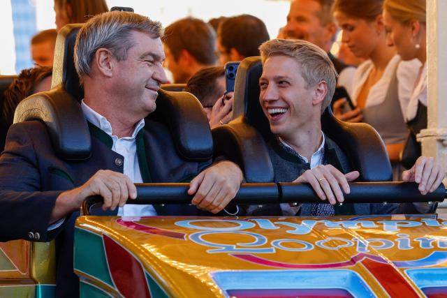 Bavaria's State Premier Markus Soeder (L) and mayor of Munich Dominik Krause (R) react after they rode a rollercoaster at Munich's annual beer festival, the Oktoberfest, on September 28, 2026 in Munich, southern Germany. The world's biggest beer festival Oktoberfest runs until October 4, 2026. (Photo by Michaela STACHE / AFP)