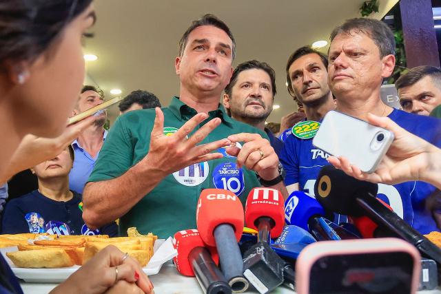 Brazil's right-wing senator and presidential candidate Flavio Bolsonaro (C), of the Liberal Party (PL), next to Sao Paulo's governor Tarcisio de Freitas speaks with the media during a campaign rally at the Sao Paulo Municipal Market in Sao Paulo, Brazil, on September 28, 2026. Brazil will hold presidential election on October 4, 2026. (Photo by Miguel SCHINCARIOL / AFP)