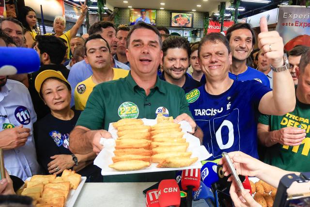 Brazil's right-wing senator and presidential candidate Flavio Bolsonaro (L), of the Liberal Party (PL), next to Sao Paulo's governor Tarcisio de Freitas holds a tray with traditional fried pastry during a campaign rally at the Sao Paulo Municipal Market in Sao Paulo, Brazil, on September 28, 2026. Brazil will hold presidential election on October 4, 2026. (Photo by Miguel SCHINCARIOL / AFP)