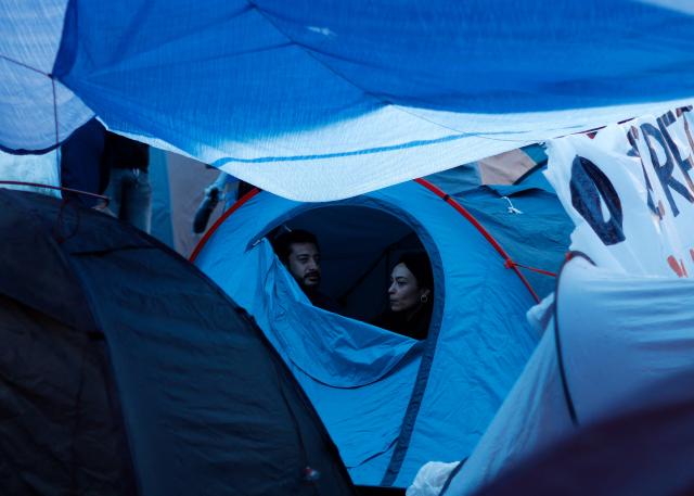 Demonstrators sit in a tent in a camp set to protest against evictions and the housing crisis in front of the Presidency of the Community of Madrid on the Puerta del Sol plaza in Madrid on September 28, 2026. Demonstrators set up around 100 tents in Madrid's Puerta del Sol and Spain's main tenants' unions on September 25 urged the government to pass a new law to tackle the country's housing crisis after an 87-year-old was evicted from her Madrid home, sparking nationwide protests. (Photo by Oscar DEL POZO / AFP)