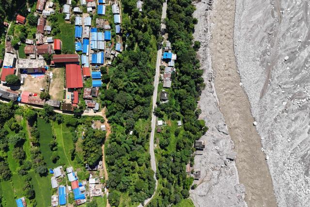 An aerial view shows damaged houses covered in sludge in the aftermath of the August 26 flash flood, at Betrawati Bazaar in Nepal's Rasuwa district on September 28, 2026. The Himalayan nation suffered one of the worst catastrophes in its history late last month when a tsunami-like flood, triggered by a high-altitude glacial mountain collapse along the Nepal-China border, cut a swathe of destruction claiming more than 1,400 lives and leaving 5,000 unaccounted for. (Photo by PRAKASH MATHEMA / AFP)