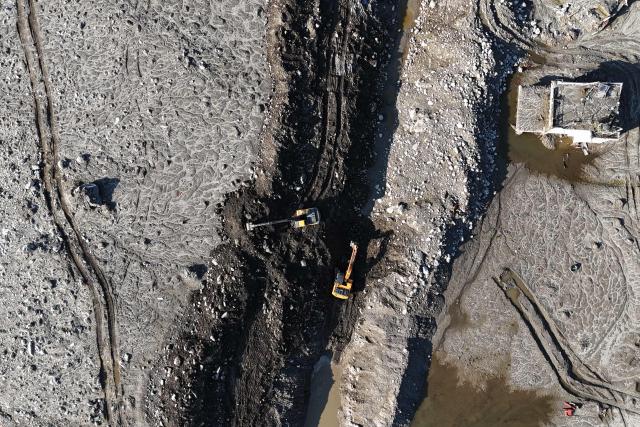 An aerial view shows workers using an excavator to remove sludge and debris from a blocked road in the aftermath of the August 26 flash flood, at Betrawati Bazaar in Nepal's Rasuwa district on September 28, 2026. The Himalayan nation suffered one of the worst catastrophes in its history late last month when a tsunami-like flood, triggered by a high-altitude glacial mountain collapse along the Nepal-China border, cut a swathe of destruction claiming more than 1,400 lives and leaving 5,000 unaccounted for. (Photo by PRAKASH MATHEMA / AFP)