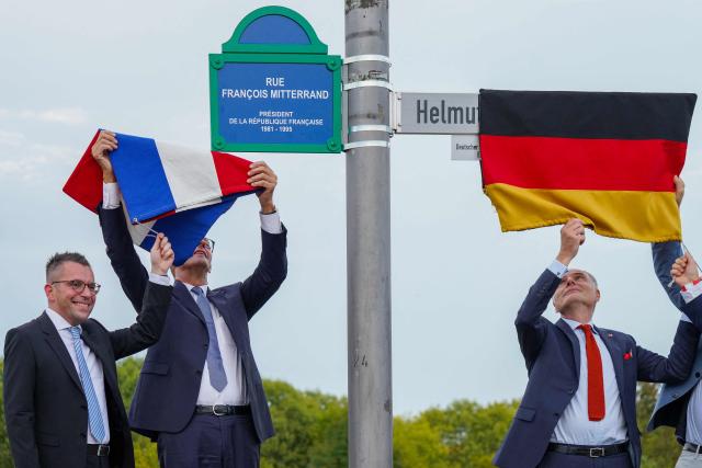 German Chancellor Friedrich Merz (C), Marc Speicher (L), Mayor of Saarlouis, and Jerome Spinoza (R), Consul General of France in Saarland, unveil the streets in honor of the late former German chancellor Helmut Kohl and the late former French president Francois Mitterrand, in Saarlouis, western Germany on September 28 2026. German Chancellor Friedrich Merz (C), Marc Speicher (L), Mayor of Saarlouis, (Photo by Andreas Schlichter / AFP)