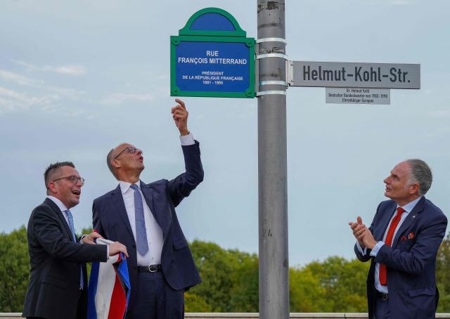 German Chancellor Friedrich Merz (C), Marc Speicher (L), Mayor of Saarlouis, and Jerome Spinoza (R), Consul General of France in Saarland, attend the inauguration ceremony of the streets in honor of the late former German chancellor Helmut Kohl and the late former French president Francois Mitterrand, in Saarlouis, western Germany on September 28 2026. German Chancellor Friedrich Merz (C), Marc Speicher (L), Mayor of Saarlouis, (Photo by Andreas Schlichter / AFP)
