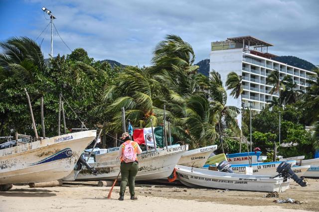 A municipal worker carries out cleanup operations near fishing boats at a beach in the tourist port of Acapulco, Guerrero state, Mexico, on September 28, 2026, ahead of the arrival of Tropical Storm Rachel. (Photo by Francisco  ROBLES / AFP)