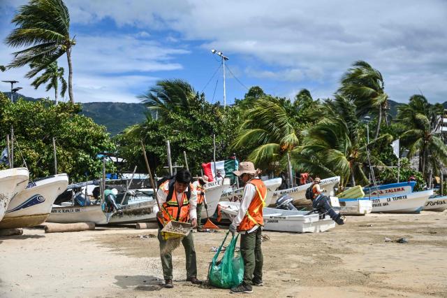 Municipal workers carry out cleanup operations near fishing boats at a beach in the tourist port of Acapulco, Guerrero state, Mexico, on September 28, 2026, ahead of the arrival of Tropical Storm Rachel. (Photo by Francisco  ROBLES / AFP)