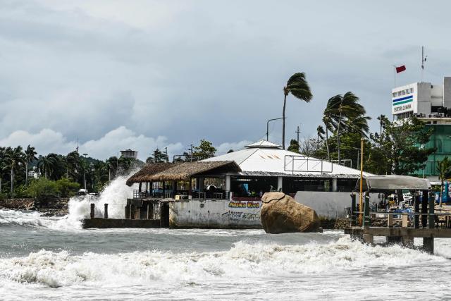 High waves crash against the waterfront as a red warning flag (R) flies outside the port captain's office in the tourist port of Acapulco, Guerrero state, Mexico, on September 28, 2026, warning vessels not to sail ahead of the arrival of Tropical Storm Rachel. (Photo by Francisco  ROBLES / AFP)
