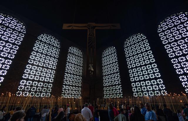 (FILES) Devotees pray in the candle room in tribute to Our Lady of Aparecida at the Basilica of the National Shrine in Aparecida, Sao Paulo State, Brazil, on April 18, 2025. A controversy surrounding a virgin worshiped in Brazil is igniting the campaign just six days before the October 4, 2026 elections, as President Lula and his rival Flavio Bolsonaro are tied in the polls and competing for religious voters in one of the countries with the largest Christian populations globally. (Photo by Roosevelt Cássio / AFP)