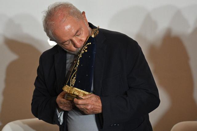 (FILES) Brazilian former president (2003-2010) and presidential candidate for the leftist Workers Party (PT), Luiz Inacio Lula da Silva, holds and kisses a statuette of Nossa Senhora de Aparecida during a meeting with nuns, priests and other members of the clergy, in Sao Paulo, Brazil, on October 17, 2022. A controversy surrounding a virgin worshiped in Brazil is igniting the campaign just six days before the October 4, 2026 elections, as President Lula and his rival Flavio Bolsonaro are tied in the polls and competing for religious voters in one of the countries with the largest Christian populations globally. (Photo by NELSON ALMEIDA / AFP)