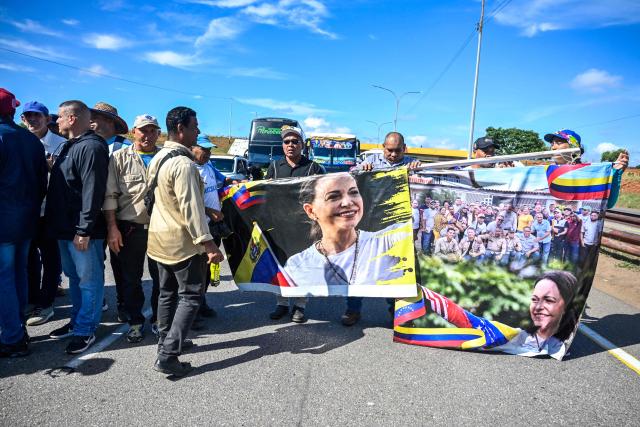 Workers and trade union members from Guayana's basic industries hold banners bearing the image of opposition leader Maria Corina Machado during a protest demanding the restoration of labour rights, free elections, the release of political prisoners and Machado's return to Venezuela in Puerto Ordaz, Bolivar state, Venezuela, on September 28, 2026. (Photo by Maryorin Mendez / AFP)