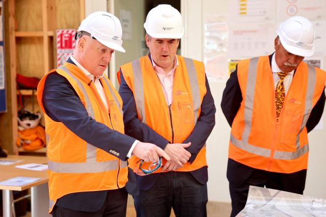 New Zealand Prime Minister Christopher Luxon (L), Lower Hutt Mayor Ken Laban (R) and Minister for Housing, Infrastructure, Transport and Hutt South MP Chris Bishop (C) visit a construction site during a general election campaign event in Lower Hutt near Wellington on September 29, 2026. New Zealanders are due to vote in the general election on November 7, 2026. (Photo by Ben STRANG / AFP)