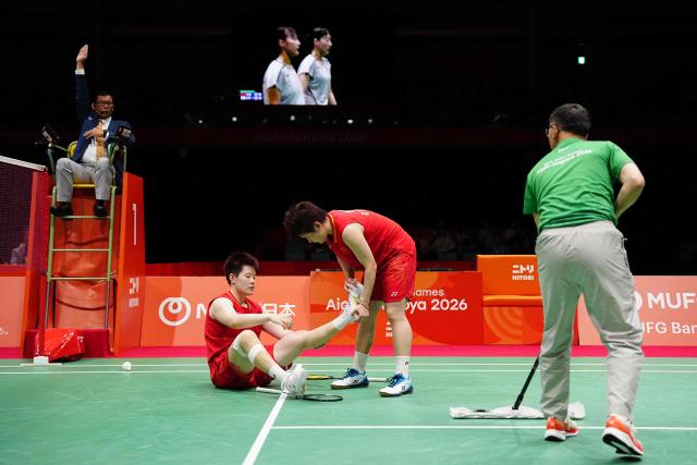 China's Liu Shengshu (centre L) stretches with the help of Tan Ning (centre R) while playing against South Korea's Lee So-hee and Baek Ha-na in the women's doubles badminton final during the 2026 Asian Games at the Ichinomiya City Municipal Gymnasium in Ichinomiya, Aichi prefecture on September 29, 2026. (Photo by Yuichi YAMAZAKI / AFP)