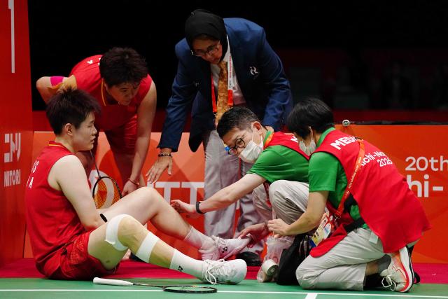 China's Liu Shengshu (bottom L) receives medical attention as she and Tan Ning (top L) play against South Korea's Lee So-hee and Baek Ha-na in the women's doubles badminton final during the 2026 Asian Games at the Ichinomiya City Municipal Gymnasium in Ichinomiya, Aichi prefecture on September 29, 2026. (Photo by Yuichi YAMAZAKI / AFP)
