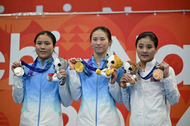 Silver medallist China's Lu Wei (L), gold medallist China's Chen Yuxi (C) and bronze medallist North Korea's Jo Jin-mi (R) pose on the podium during the victory ceremony of the women's 10m platform final diving event during the 2026 Asian Games at the Tokyo Aquatics Centre in Tokyo on September 29, 2026. (Photo by ANDREW CABALLERO-REYNOLDS / AFP)