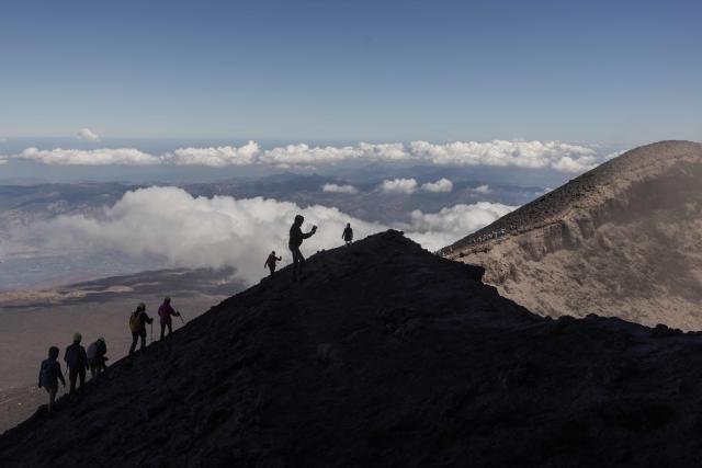 Visitors climb Mount Etna as smoke rises from its volcano in Catania, on the Mediterranean island of Sicily, on September 28, 2026. (Photo by Roman PILIPEY / AFP)