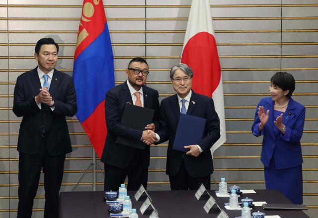 Mongolia's Prime Minister Nyam-Osoryn Uchral (L) and Japan's Prime Minister Sanae Takaichi applaud as Mongolia's Finance Minister Zagdjav Mendsaikhan (2nd L) and Japan's Ambassador to Mongolia Masaru Igawahara exchange documents during a meeting in Tokyo on September 29, 2026. (Photo by Kim Kyung-Hoon / POOL / AFP)