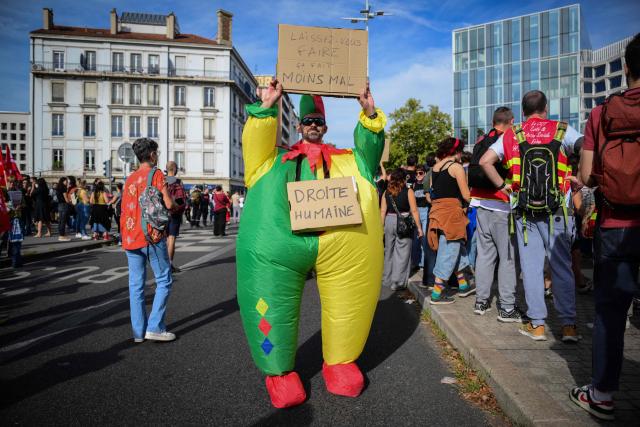 A protester in costume holds a placard which reads "Don't resist, it will hurt less" as he takes part in a rally during a day of nationwide public sector strikes and demonstrations, in Lyon, on September 29, 2026. Public sector workers, including firefighters, hold a one-day strike and demonstrations across France on September 29 in response to a call from a broad inter-union coalition, with the aim of putting pressure on the government two days before the presentation of the draft budget for 2027. (Photo by OLIVIER CHASSIGNOLE / AFP)