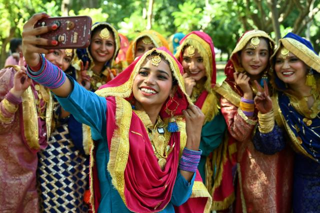 Students in traditional Punjabi dresses take selfies after their performance during the 'Giddha' folk dance competition at a university in Amritsar on September 29, 2026. (Photo by Narinder NANU / AFP)