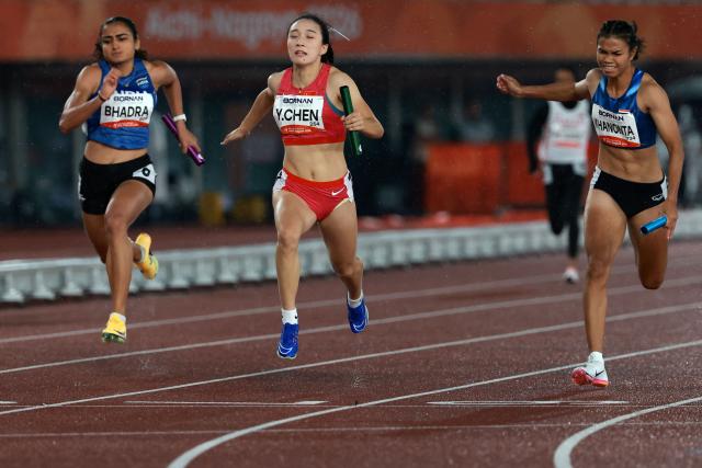 China's Chen Yujie (C) crosses the finish line ahead of Thailand's Jirapat Khanonta (R) and India's Harita Bhadra to win the mixed 4x100m relay final during the 2026 Asian Games at Nagoya City Mizuho Park Athletic Stadium in Nagoya, Aichi Prefecture on September 29, 2026. (Photo by DAVID GRAY / AFP)