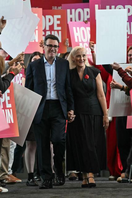Britain's Prime Minister Andy Burnham (L) and his wife Marie-France van Heel (R) are welcomed upon arrival ahead of his speech on the third day of the annual Labour Party conference in Liverpool, north-west England, on September 29, 2026. (Photo by Paul ELLIS / AFP)