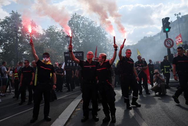 Firefighters light flares during a rally as part of a day of nationwide public sector strikes and demonstrations, in Paris, on September 29, 2026. Public sector workers, including firefighters, hold a one-day strike and demonstrations across France on September 29 in response to a call from a broad inter-union coalition, with the aim of putting pressure on the government two days before the presentation of the draft budget for 2027. (Photo by Anne-Christine POUJOULAT / AFP)