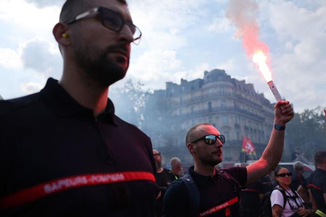 Firefighters light flares during a rally as part of a day of nationwide public sector strikes and demonstrations, in Paris, on September 29, 2026. Public sector workers, including firefighters, hold a one-day strike and demonstrations across France on September 29 in response to a call from a broad inter-union coalition, with the aim of putting pressure on the government two days before the presentation of the draft budget for 2027. (Photo by Anne-Christine POUJOULAT / AFP)