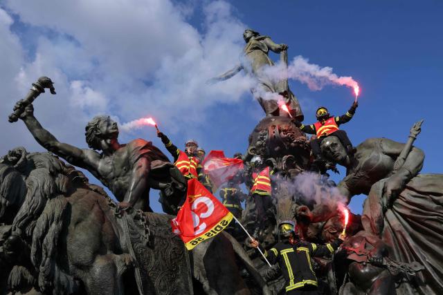 Firefighters hold flares as they gather on the Triumph of the Republic monument at Place de la Nation during a day of nationwide public sector strikes and demonstrations in Paris on September 29, 2026. Public sector workers, including firefighters, hold a one-day strike and demonstrations across France on September 29 in response to a call from a broad inter-union coalition, with the aim of putting pressure on the government two days before the presentation of the draft budget for 2027. (Photo by Thomas SAMSON / AFP)