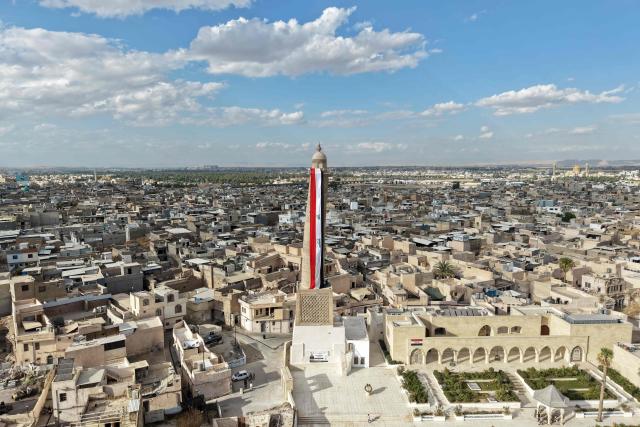 A giant Iraqi flag hangs off the reconstructed 12th century "Hadba" leaning minaret at the historic Great Mosque of al-Nuri in the old city of Mosul on September 29, 2026 as Iraq marks the withdrawal of the US-led anti-Islamic State coalition forces from the country. After more than a decade, the US-led coalition is ending its mission in Iraq, having helped save the country from jihadists but causing persistent friction in the country. Baghdad and Washington agreed in 2024 to wind down the coalition's mission, and its troops withdrew gradually from bases across the country, restricting their presence to the autonomous northern Kurdistan region. Iraqi Prime Minister Ali al-Zaidi declared that October 1, the day following the coalition's departure, should be celebrated as Sovereignty Day. (Photo by Zaid AL-OBEIDI / AFP)