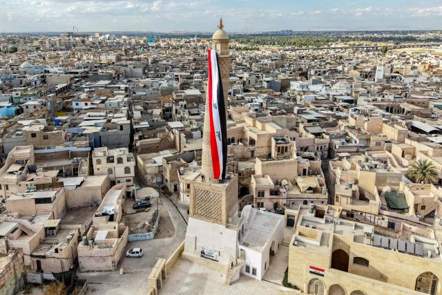A giant Iraqi flag hangs off the reconstructed 12th century "Hadba" leaning minaret at the historic Great Mosque of al-Nuri in the old city of Mosul on September 29, 2026 as Iraq marks the withdrawal of the US-led anti-Islamic State coalition forces from the country. After more than a decade, the US-led coalition is ending its mission in Iraq, having helped save the country from jihadists but causing persistent friction in the country. Baghdad and Washington agreed in 2024 to wind down the coalition's mission, and its troops withdrew gradually from bases across the country, restricting their presence to the autonomous northern Kurdistan region. Iraqi Prime Minister Ali al-Zaidi declared that October 1, the day following the coalition's departure, should be celebrated as Sovereignty Day. (Photo by Zaid AL-OBEIDI / AFP)