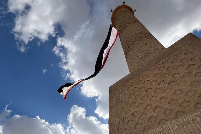 A giant Iraqi flag hangs off the reconstructed 12th century "Hadba" leaning minaret at the historic Great Mosque of al-Nuri in the old city of Mosul on September 29, 2026 as Iraq marks the withdrawal of the US-led anti-Islamic State coalition forces from the country. After more than a decade, the US-led coalition is ending its mission in Iraq, having helped save the country from jihadists but causing persistent friction in the country. Baghdad and Washington agreed in 2024 to wind down the coalition's mission, and its troops withdrew gradually from bases across the country, restricting their presence to the autonomous northern Kurdistan region. Iraqi Prime Minister Ali al-Zaidi declared that October 1, the day following the coalition's departure, should be celebrated as Sovereignty Day. (Photo by Zaid AL-OBEIDI / AFP)