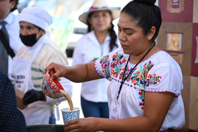 A corn producer serves a corn-based drink to visitors during National Corn Day celebrations at the Zocalo in Mexico City on September 29, 2026. The Mexican government, together with farmers, peasant organisations and civil society groups, is showcasing products derived from Mexico's 64 native maize varieties, considered a symbol of national identity and cultural heritage. (Photo by Yuri CORTEZ / AFP)