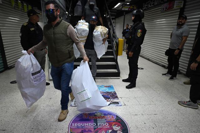 Agents from the Secretariat of Citizen Security and the Mexican Institute of Industrial Property provide security as colleagues load packages of allegedly pirated goods seized during an operation at a shopping center in Mexico City on September 29, 2026. (Photo by Yuri CORTEZ / AFP)