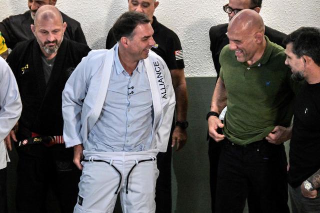 Brazil's right-wing senator and presidential candidate Flavio Bolsonaro (C) of the Liberal Party (PL) puts on a jiu-jitsu gi during a meeting with practitioners at a gym during a campaign rally in Sao Paulo, Brazil, on September 29, 2026. Brazil will hold presidential election on October 4, 2026. (Photo by Nelson ALMEIDA / AFP)
