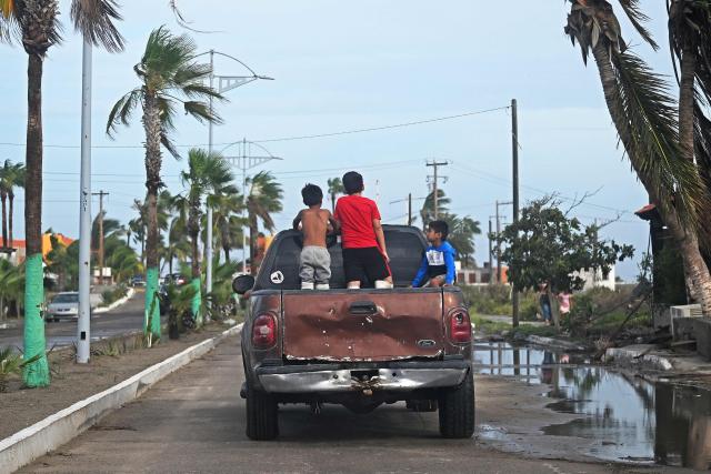 Young boys ride in the back of a pick-up truck in Puerto San Carlos, Baja California Sur state, Mexico, on September 29, 2026, following the arrival of Hurricane Polo. Hurricane Polo made landfall on Mexico's Baja California peninsula on September 29, cutting power and causing flooding as the sea breached coastal defenses. The Category 3 storm is the latest in a busy storm season turbo-charged by the El Nino weather phenomenon, which has caused unprecedented warming in the equatorial Pacific. (Photo by Carl de Souza / AFP)
