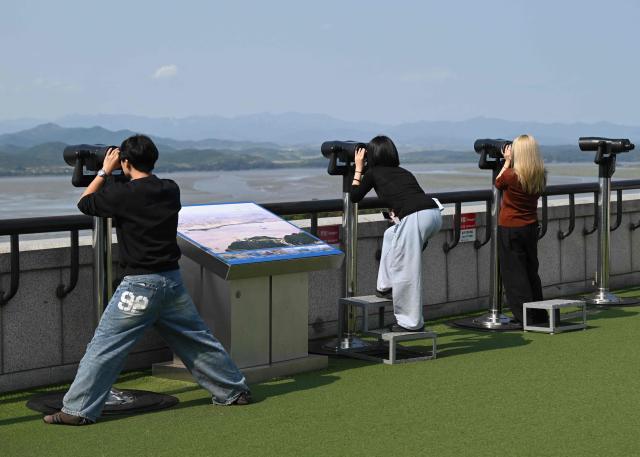 Visitors use binoculars to watch the North Korean side of the Demilitarised Zone (DMZ) dividing the two Koreas, from a South Korean observatory in Paju on September 30, 2026. Seoul's military demanded an apology from North Korea on September 30, blaming them for a recent explosion in the demilitarised zone that severely injured three South Korean soldiers, a charge Pyongyang denies. (Photo by Jung Yeon-je / AFP)