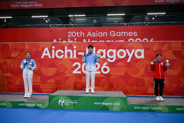 Silver medallist China's Chen Jia (L), gold medallist China's Chen Yiwen (C) and bronze medallist Japan's Sayaka Mikami (R) pose on the podium during the victory ceremony of the women's 3m springboard final diving event during the 2026 Asian Games at the Tokyo Aquatics Centre in Tokyo on September 30, 2026. (Photo by ANDREW CABALLERO-REYNOLDS / AFP)